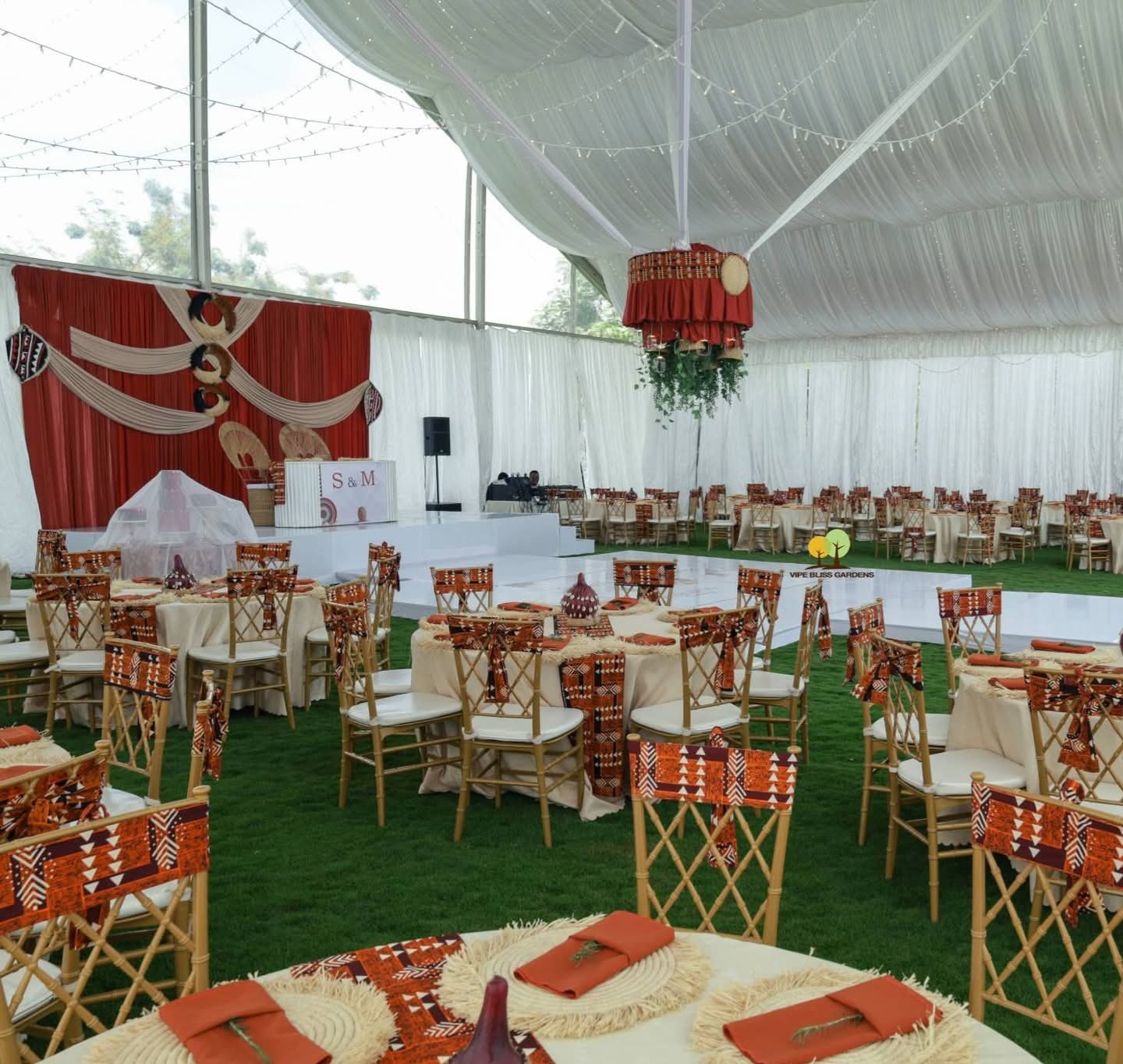 Traditional celebration reception with patterned chairs, dressed round tables and white marquee draping