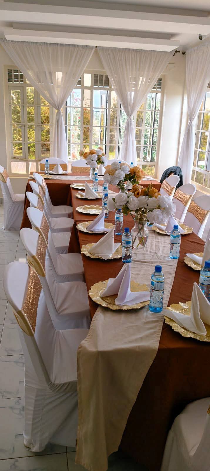 Bright conference room with dressed tables, white chairs and floral arrangements