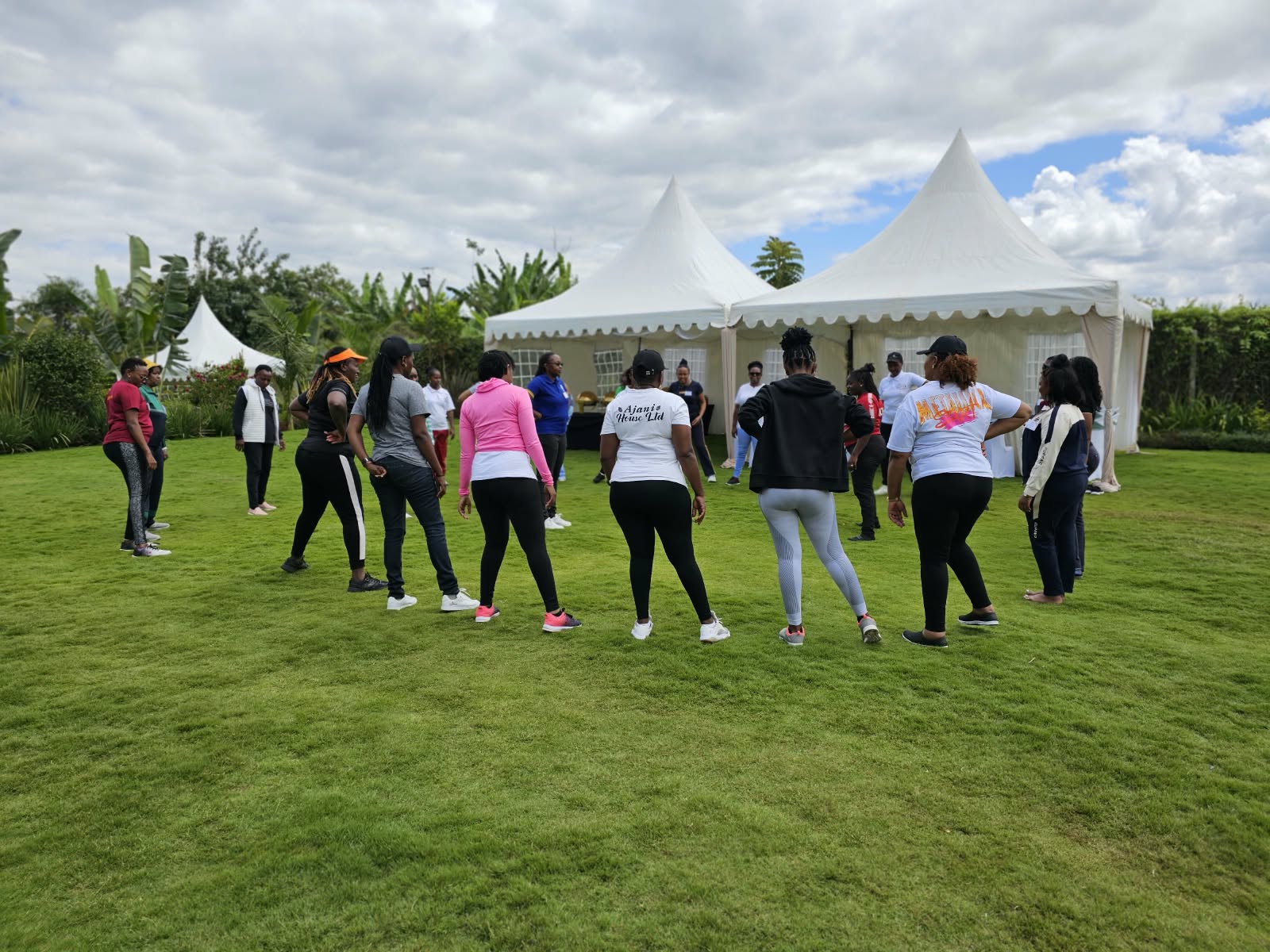 Group gathering for an outdoor team-building activity beside white tents at Vipe Bliss Gardens