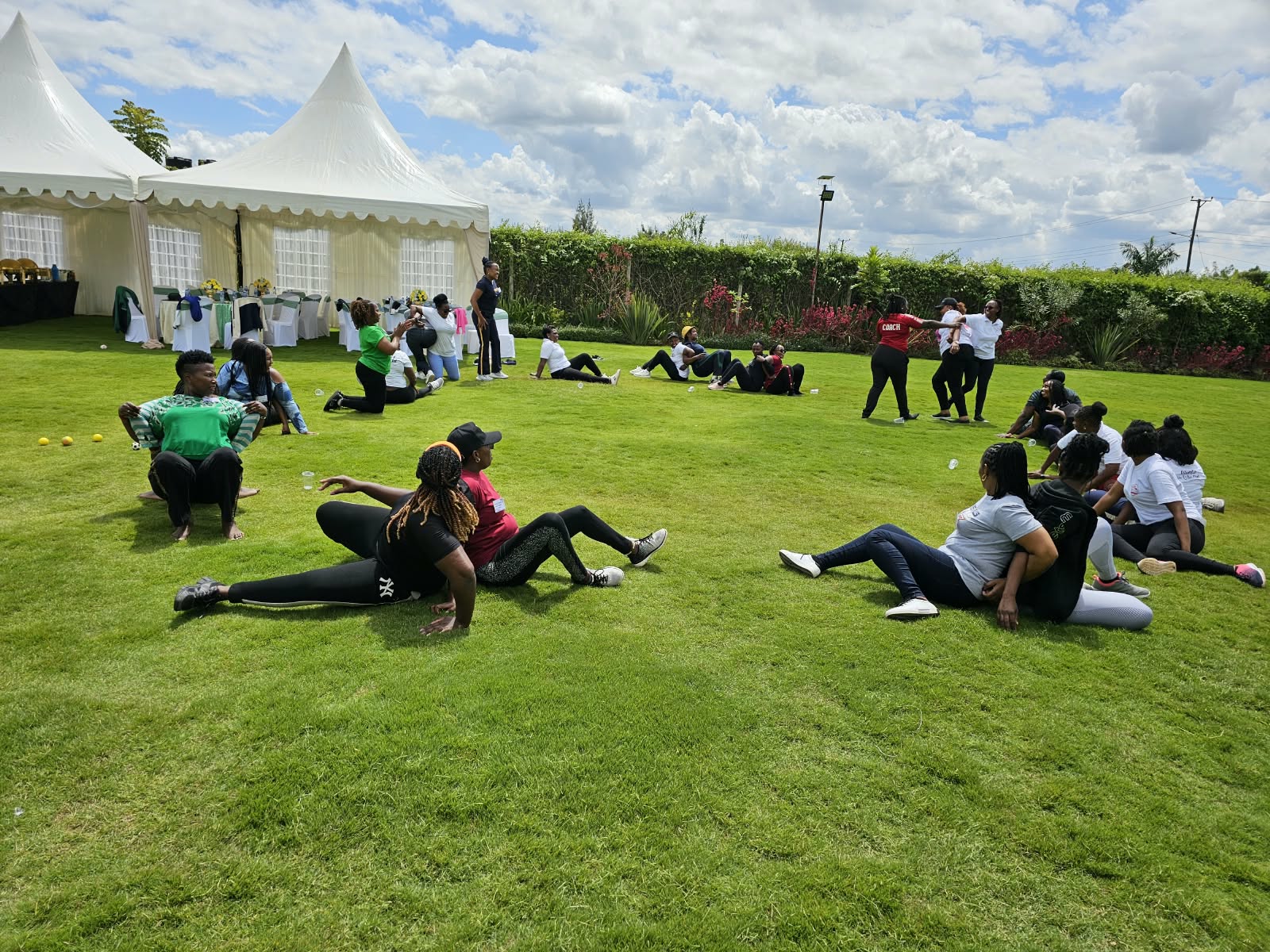 Colleagues taking part in a seated team-building game across the sunny garden lawn