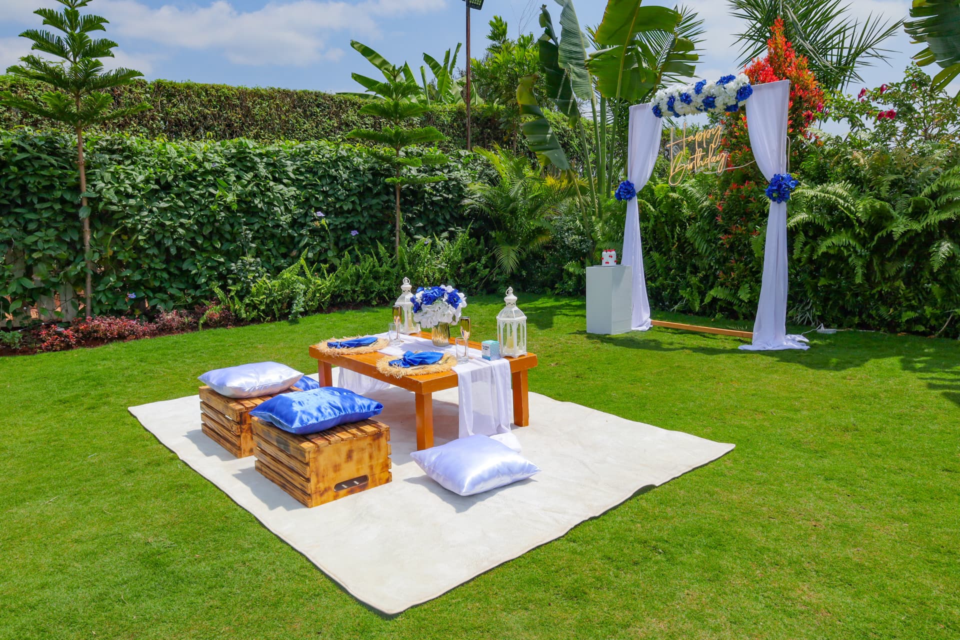 Blue and white birthday picnic setting on the sunny garden lawn