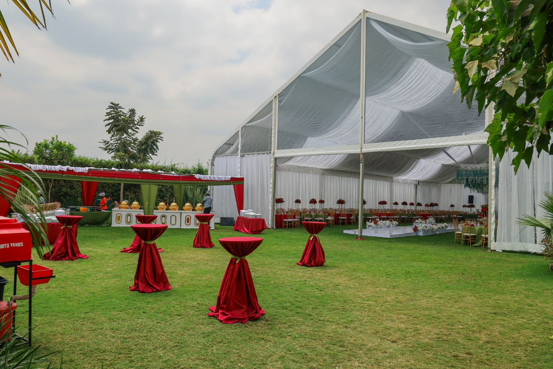 Large marquee, cocktail tables and catering area arranged across the green lawn
